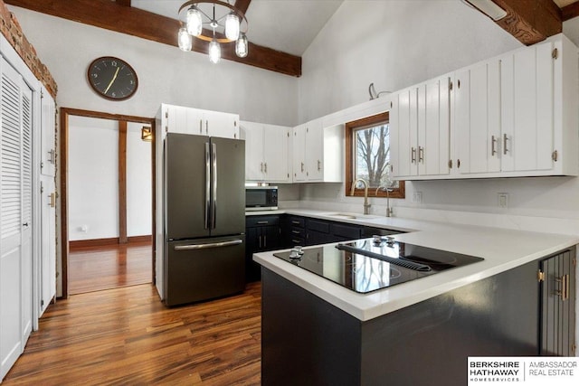 kitchen with dark wood-style floors, beam ceiling, light countertops, appliances with stainless steel finishes, and a sink