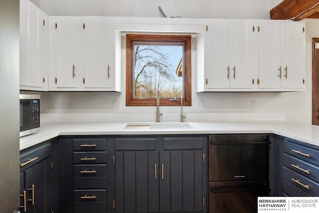 kitchen featuring white cabinets, dishwasher, stainless steel microwave, light countertops, and a sink