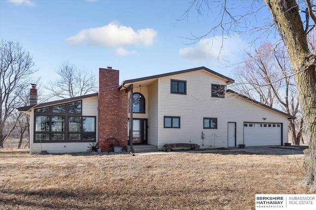 view of front of property with driveway, a chimney, an attached garage, and a sunroom