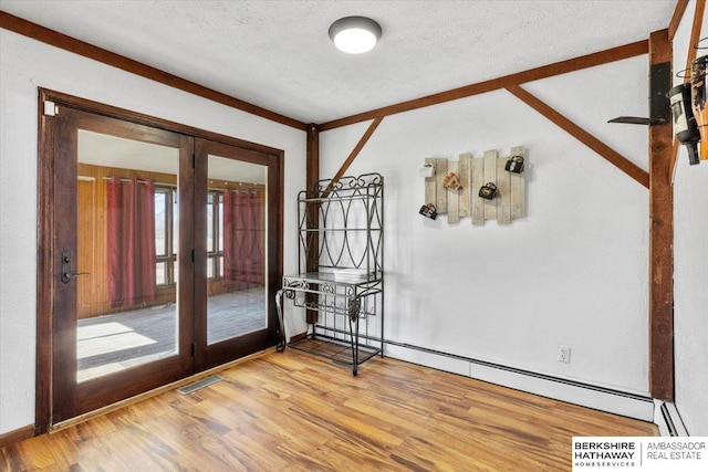 empty room with a textured ceiling, french doors, wood finished floors, and visible vents