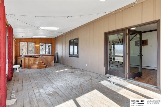 unfurnished sunroom with a baseboard heating unit and a skylight