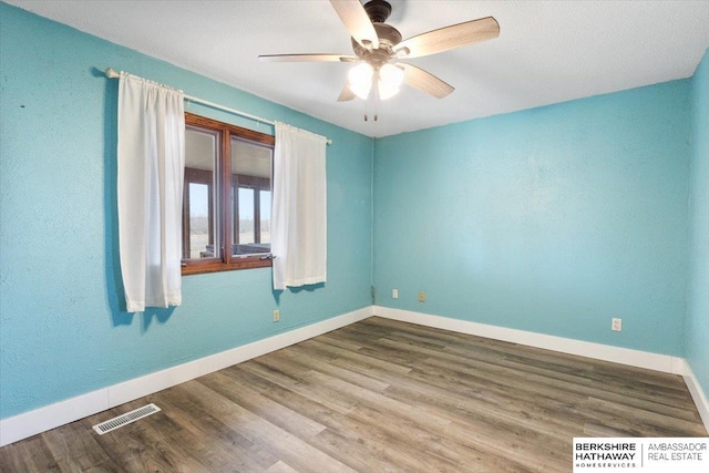 unfurnished room with visible vents, ceiling fan, baseboards, and wood finished floors