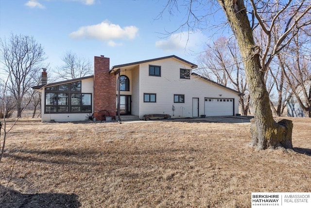 view of front of house featuring a garage, a sunroom, and a chimney