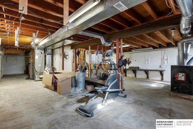 unfinished basement featuring a wood stove, visible vents, and heating unit