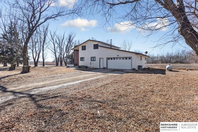 view of property exterior with an attached garage and dirt driveway