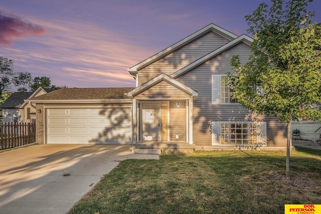 tri-level home with brick siding, a front yard, fence, a garage, and driveway