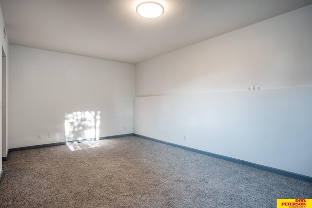 carpeted empty room featuring baseboards