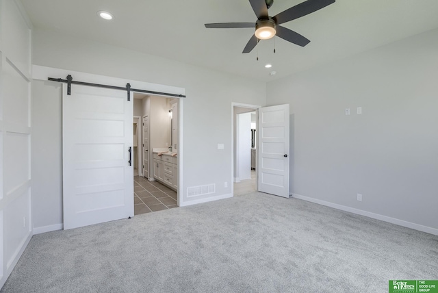 unfurnished bedroom featuring a barn door, recessed lighting, carpet flooring, visible vents, and baseboards