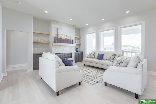 living area featuring light wood-type flooring, a stone fireplace, and recessed lighting