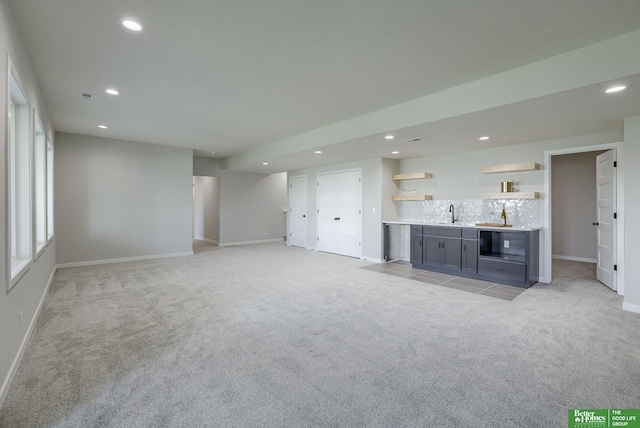 unfurnished living room featuring indoor wet bar, recessed lighting, light colored carpet, and baseboards