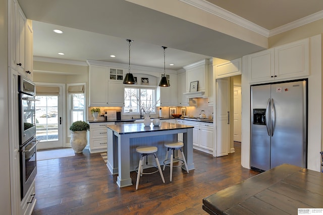 kitchen featuring dark wood-style flooring, white cabinetry, appliances with stainless steel finishes, dark countertops, and crown molding