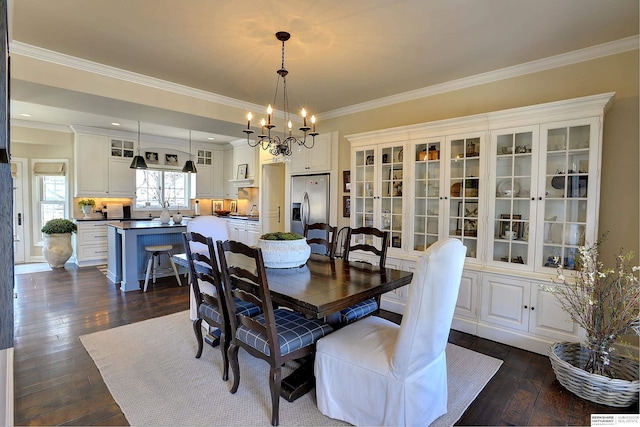 dining space featuring ornamental molding, a chandelier, and dark wood finished floors