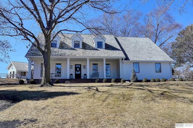 new england style home with covered porch and a front lawn