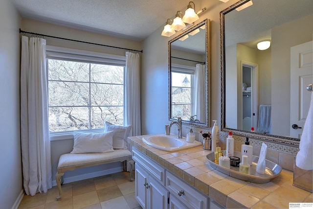 bathroom with baseboards, a textured ceiling, and vanity