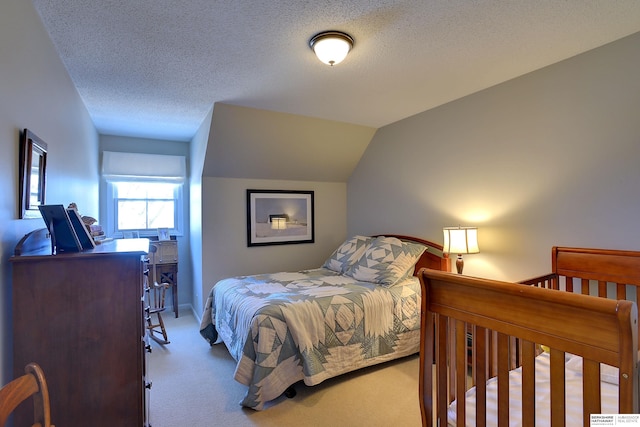 carpeted bedroom with vaulted ceiling and a textured ceiling