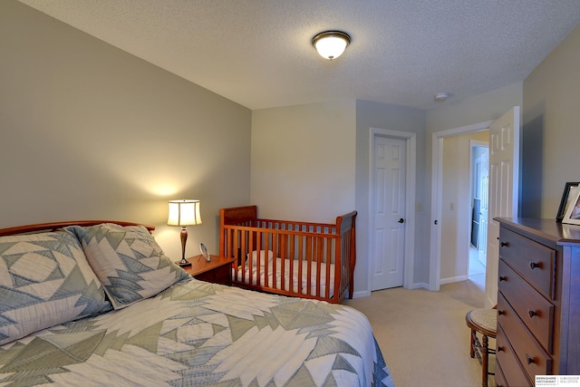 bedroom featuring light carpet, a textured ceiling, and baseboards