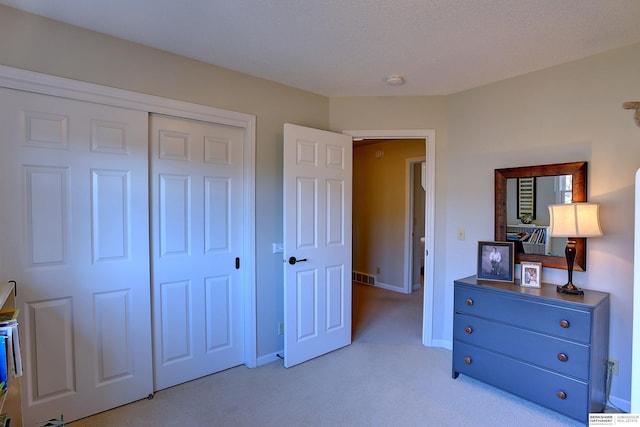 bedroom with a closet, visible vents, light carpet, and baseboards