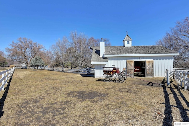 view of yard featuring a barn, fence, and an outdoor structure