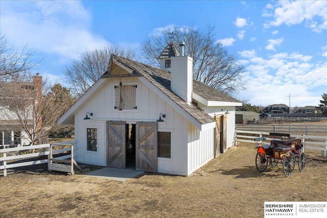 rear view of property with an outbuilding, a barn, fence, board and batten siding, and a chimney