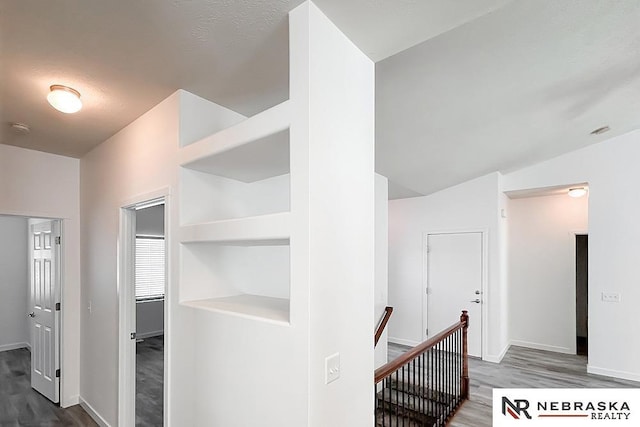 hallway featuring baseboards, an upstairs landing, and wood finished floors