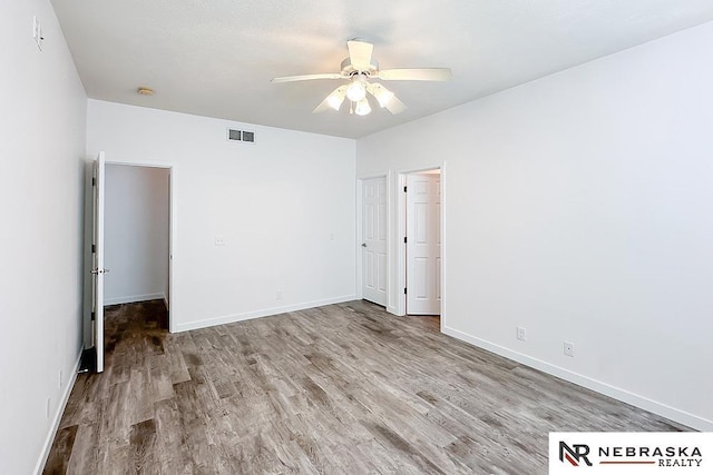 unfurnished bedroom featuring baseboards, visible vents, ceiling fan, and wood finished floors