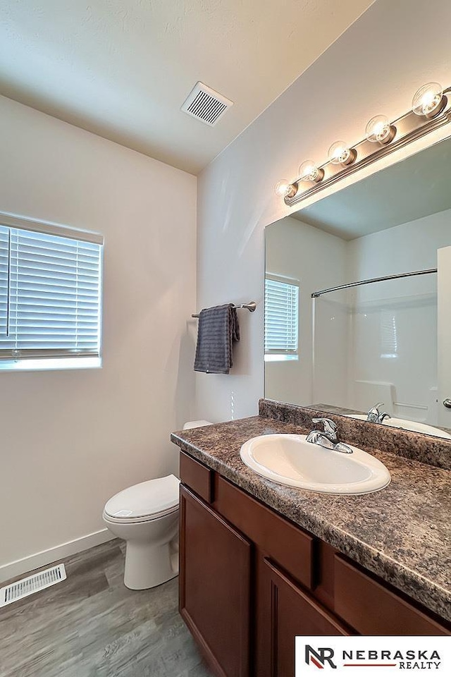 bathroom featuring visible vents, vanity, toilet, and wood finished floors