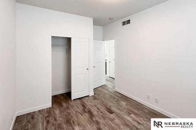 unfurnished bedroom with baseboards, a closet, visible vents, and wood finished floors