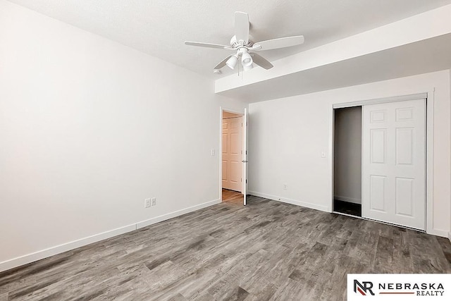 unfurnished bedroom featuring a closet, ceiling fan, baseboards, and wood finished floors