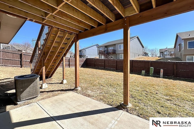 view of patio / terrace featuring a fenced backyard, stairs, a residential view, and cooling unit