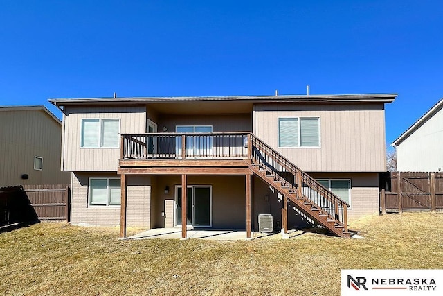 rear view of property with brick siding, fence, stairs, a lawn, and a patio area