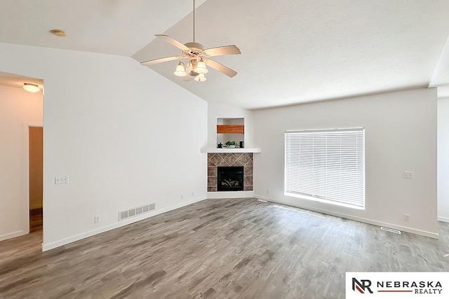 unfurnished living room with a fireplace, lofted ceiling, visible vents, ceiling fan, and wood finished floors