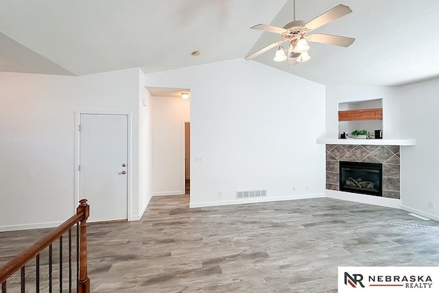 unfurnished living room featuring baseboards, visible vents, a tile fireplace, wood finished floors, and vaulted ceiling