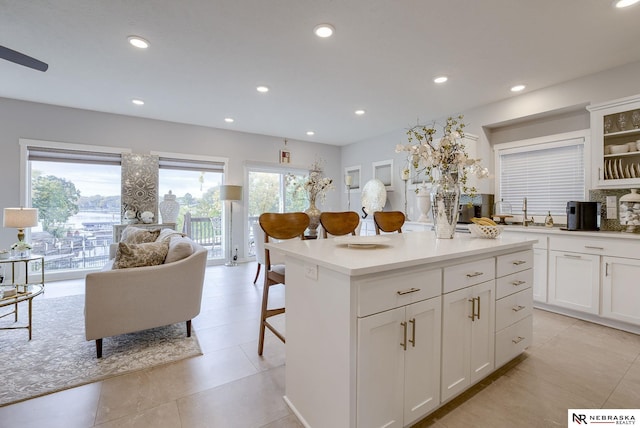 kitchen featuring a kitchen breakfast bar, a kitchen island, white cabinets, and recessed lighting