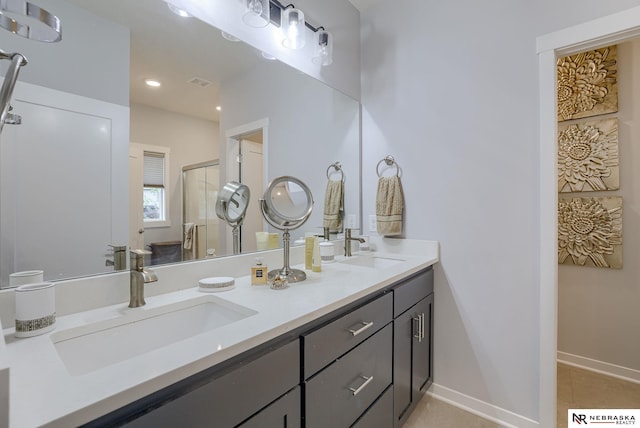 full bath featuring a sink, a shower stall, baseboards, and double vanity