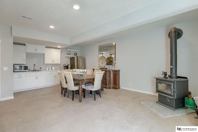 dining room with visible vents, recessed lighting, a wood stove, and baseboards