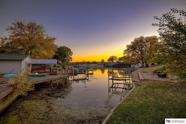 dock area with a water view, boat lift, and a lawn