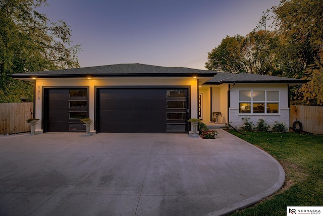 prairie-style home featuring a garage, brick siding, fence, concrete driveway, and a lawn