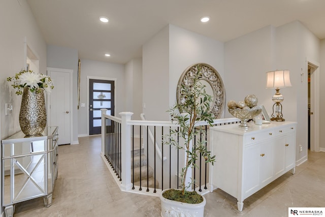 hall with recessed lighting, baseboards, and an upstairs landing