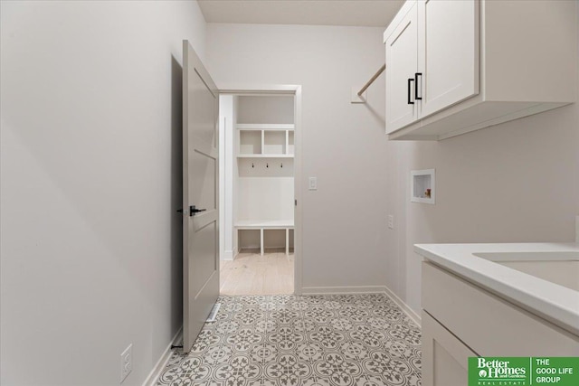 clothes washing area featuring hookup for a washing machine, cabinet space, and baseboards