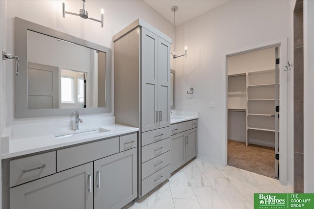 bathroom featuring marble finish floor, baseboards, a walk in closet, and vanity