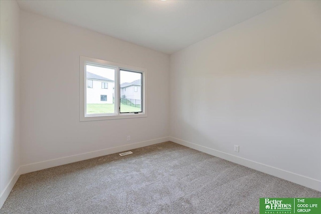 unfurnished room with carpet floors, visible vents, and baseboards