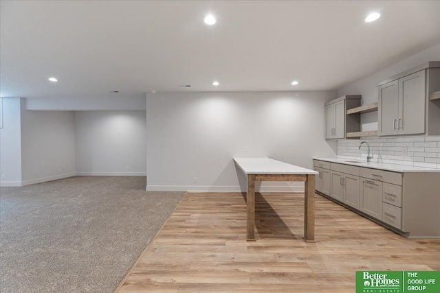 kitchen with tasteful backsplash, baseboards, gray cabinetry, a sink, and recessed lighting