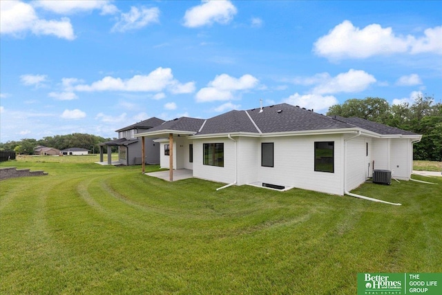 rear view of property featuring central AC unit, a shingled roof, a lawn, a pergola, and a patio area