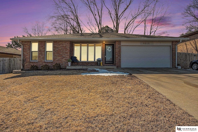 ranch-style house with a garage, brick siding, concrete driveway, and fence