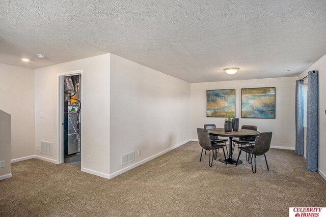 carpeted dining space featuring a textured ceiling, visible vents, and baseboards