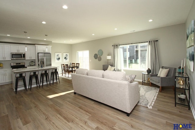 living area featuring recessed lighting, baseboards, and light wood finished floors