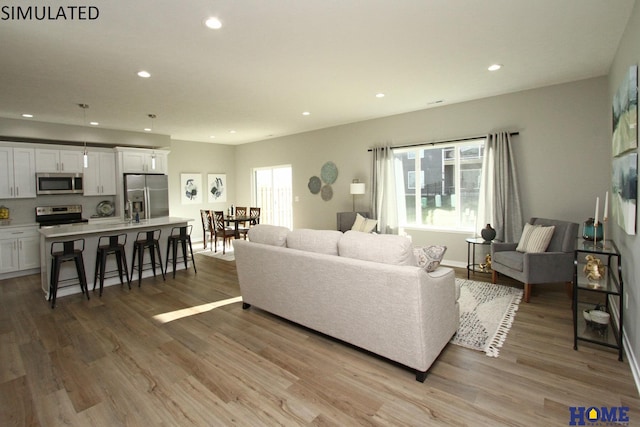 living area with baseboards, light wood-style flooring, and recessed lighting