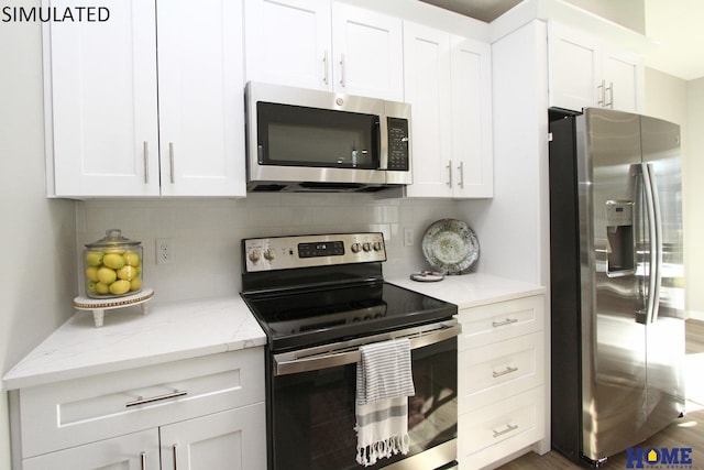 kitchen with tasteful backsplash, appliances with stainless steel finishes, white cabinets, and light stone counters