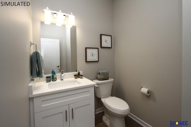 bathroom featuring toilet, baseboards, and vanity