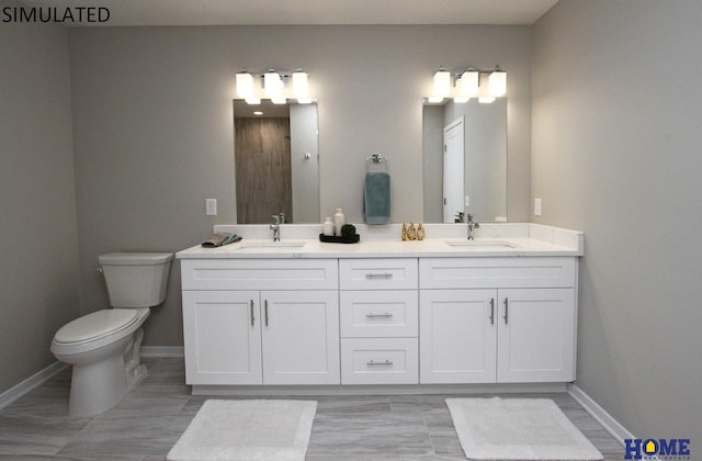 bathroom featuring double vanity, a sink, toilet, and baseboards